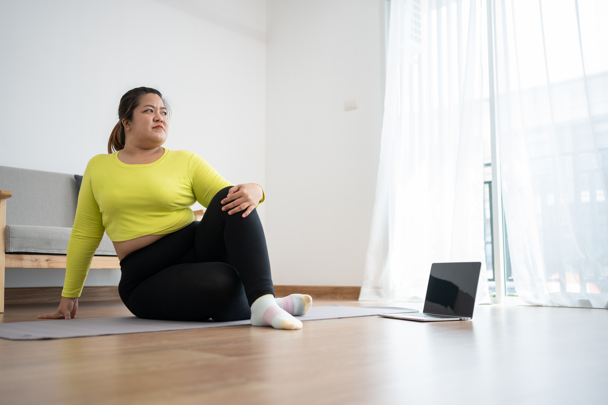 Asian overweight woman doing stretching exercise at home on fitness mat. Home activity training, online fitness class. Stretching training workout on yoga mat at home for good health and body shape.